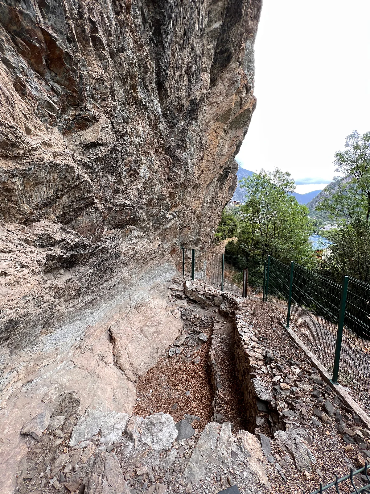 La balma de la Margineda, abrigo bajo la roca con restos prehistóricos, junto a un camino vallado