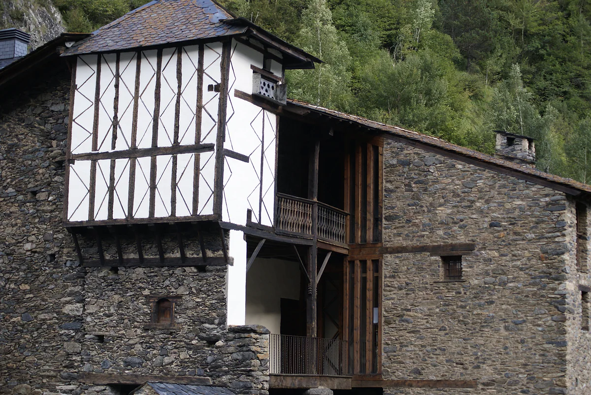 Cal Pal en La Cortinada, casa señorial de piedra con galerías de madera y torre de entramado blanco