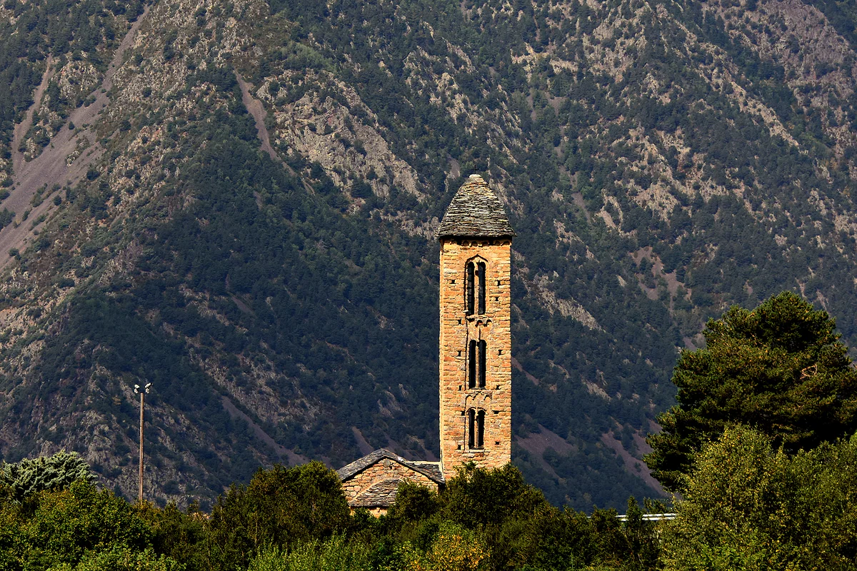 El campanario de Sant Miquel d'Engolasters se recorta contra la ladera de pinos sobre Escaldes