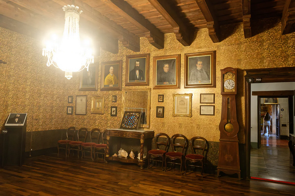 Salón principal de la Casa d'Areny-Plandolit, en Ordino, con retratos, lámpara de araña y reloj de pie