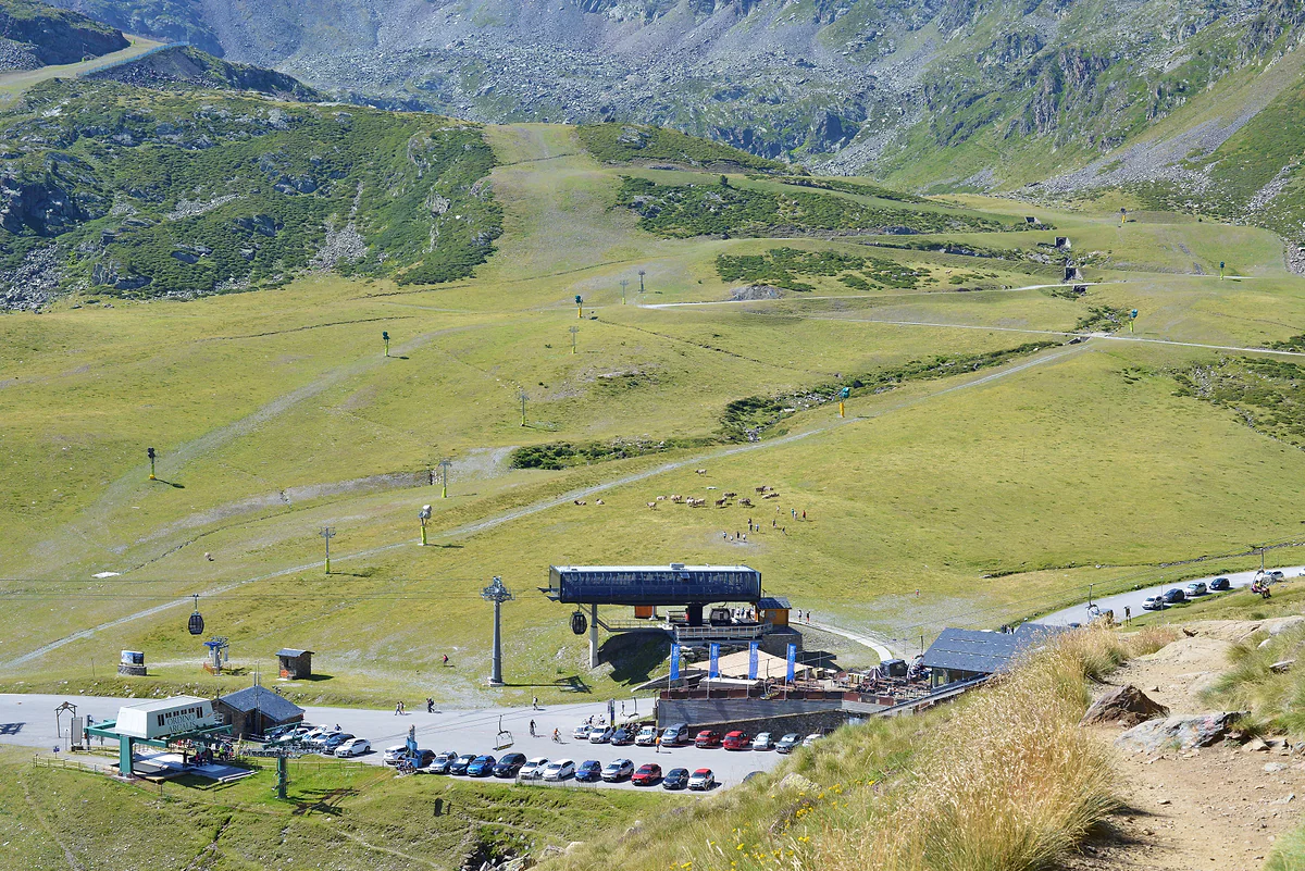 Telesillas y pistas de Ordino Arcalís en verano, cubiertas de hierba, con el aparcamiento de la estación