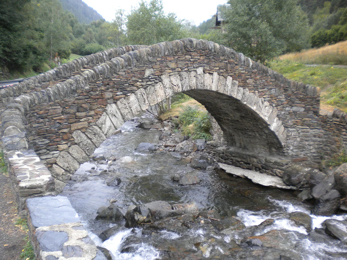 Puente de piedra de arco muy apuntado sobre el río Valira del Nord a su paso por Ordino