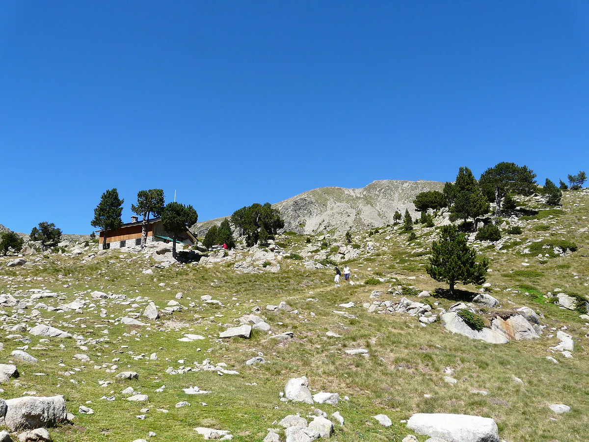 El refugio de la Pera entre pinos y rocas, en la montaña de Sant Julià de Lòria, con cielo azul