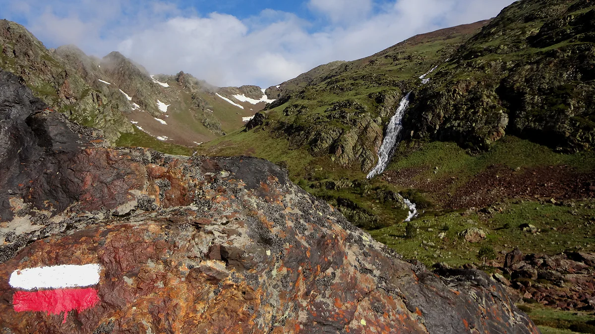 Marca roja y blanca de gran recorrido en la subida al Comapedrosa, con una cascada en el valle
