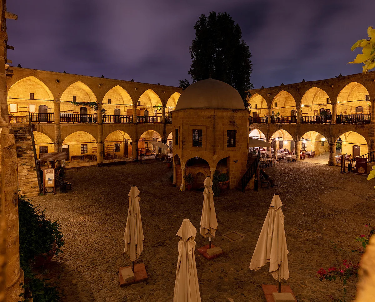 The Büyük Han in North Nicosia lit up at night, its golden arcades ringing the courtyard and the central mosque