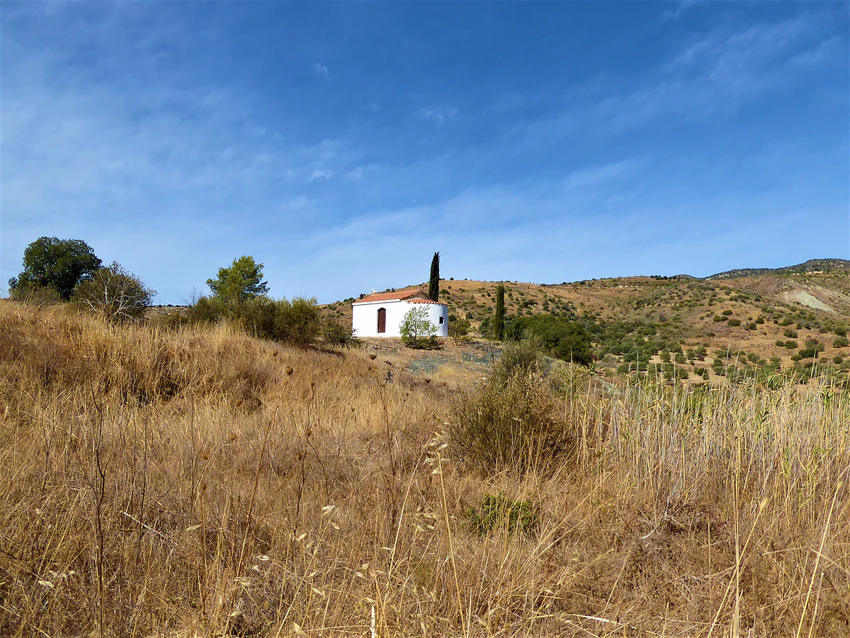 The white chapel of Agios Mamas beside a cypress among dry hills of the Diarizos Valley, near Agios Georgios village