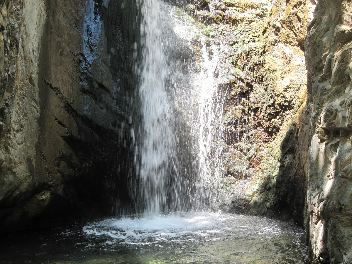 Millomeris waterfall near Platres, falling between walls of dark rock into a pool in the Troodos Mountains