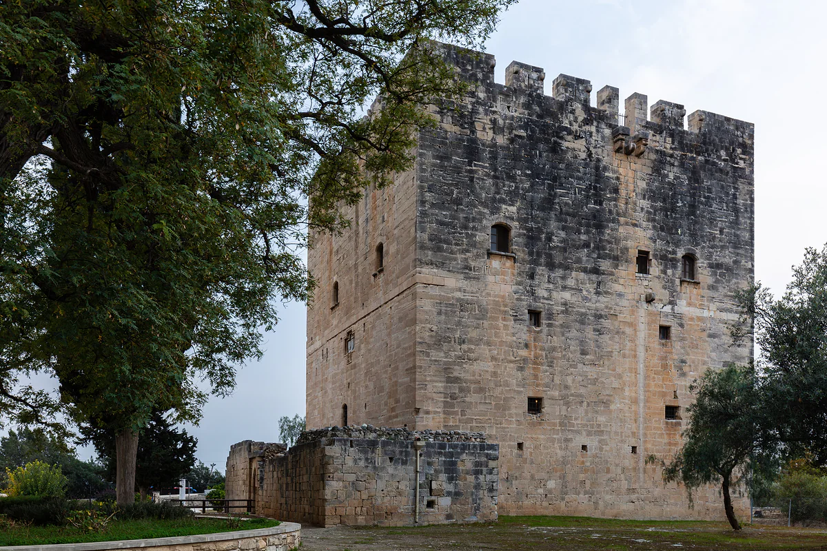 The square stone keep of Kolossi Castle, with battlements on top, among trees west of Limassol in Cyprus