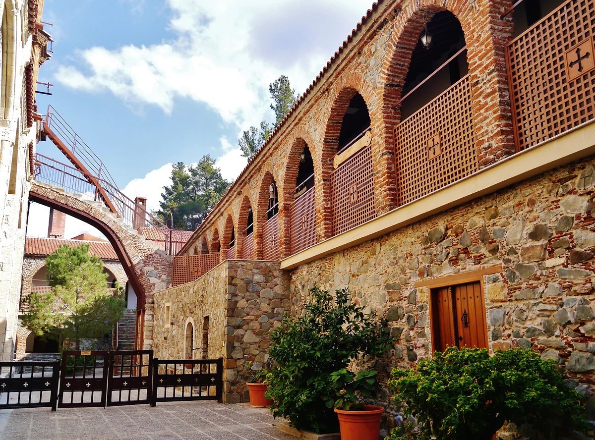 The cloister of Machairas Monastery, with brick-arched galleries, stone walls and potted plants in the courtyard