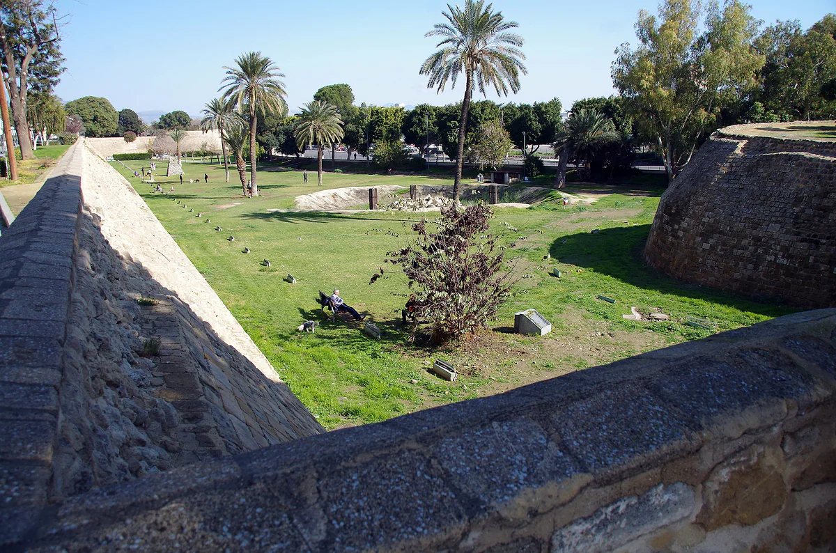 The landscaped moat below the Venetian walls of Nicosia, with angled stone ramparts, lawns and palm trees