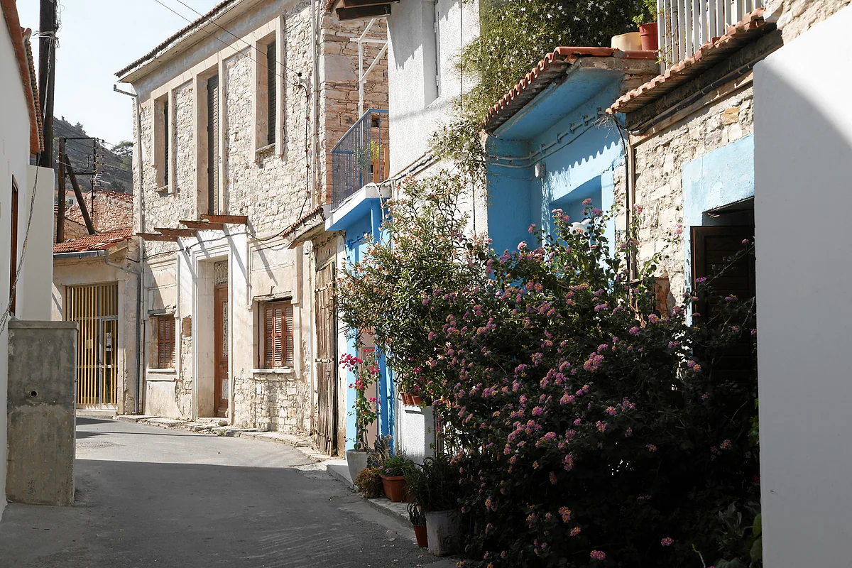 A street in Pano Lefkara with typical pale stone houses, blue doors, balconies and bougainvillea in flower