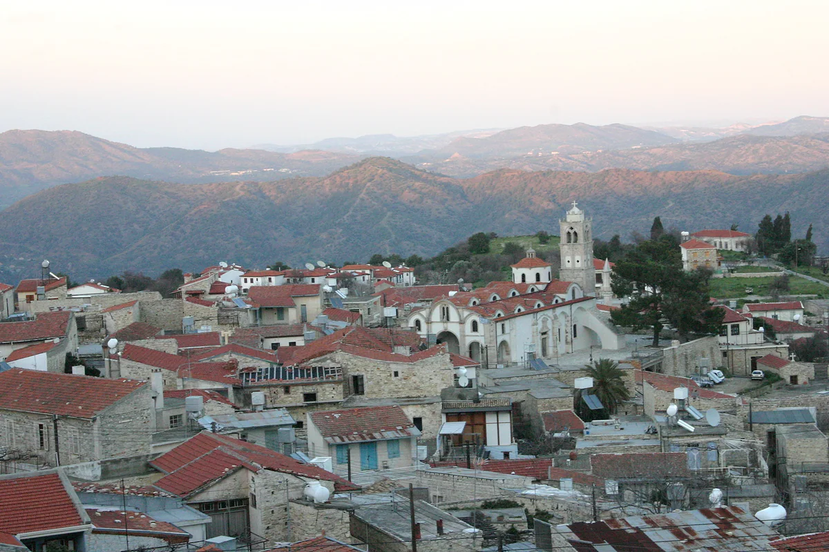 Lefkara seen from above, with its red roofs, the church bell tower and the inland mountains in the background