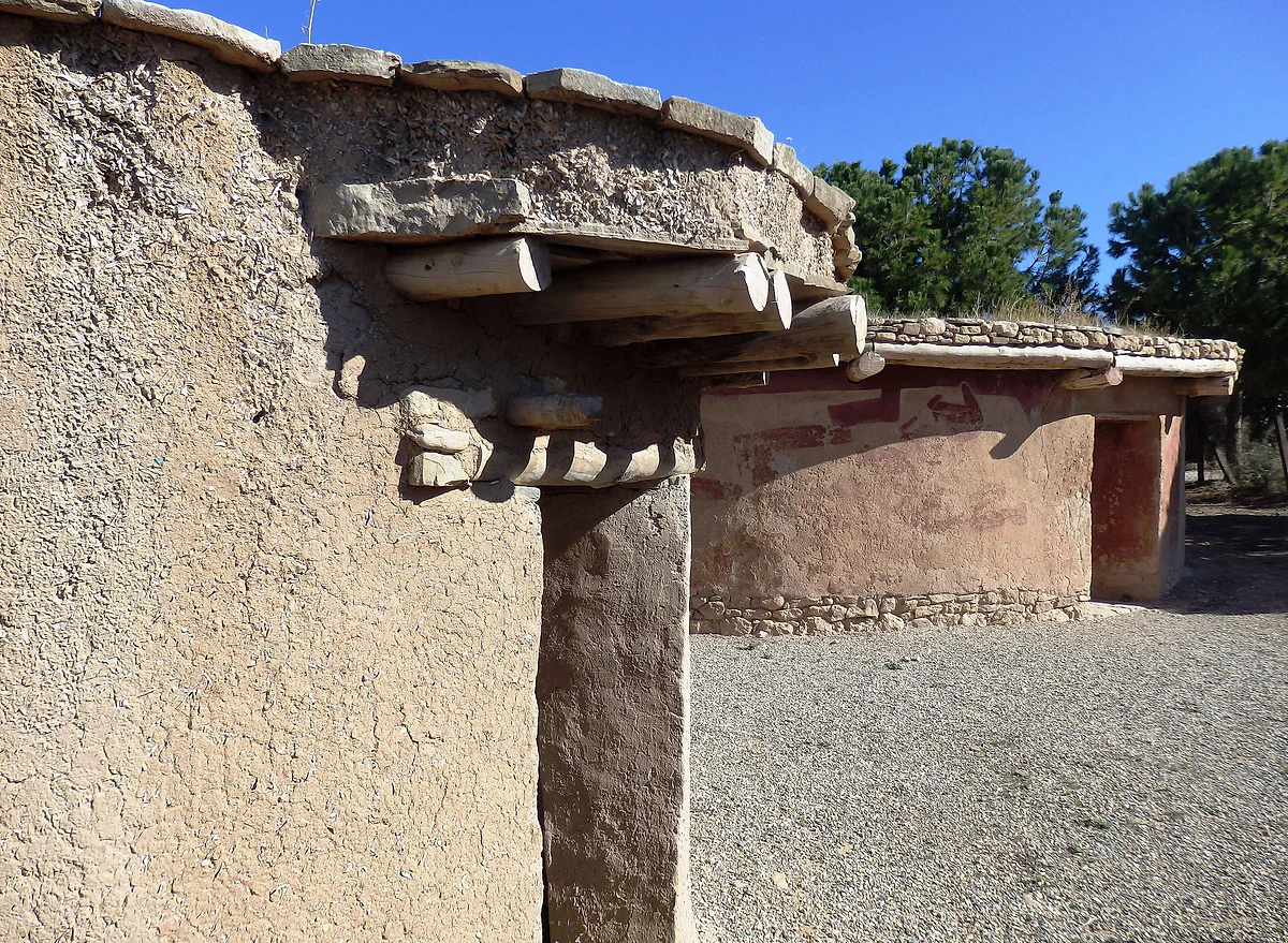 Two reconstructed round houses at the Chalcolithic village of Lempa, of mud and stone, with flat beamed roofs and pines behind