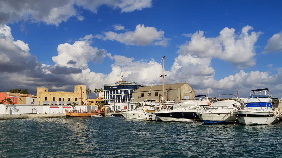 Yachts moored at Limassol Marina, next to the old port, with low buildings behind and a sky full of white clouds