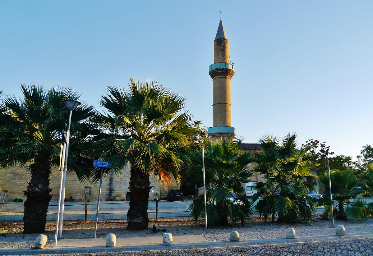 The Ömeriye Mosque in Nicosia, a former Augustinian church, with its slender minaret among palm trees at dusk