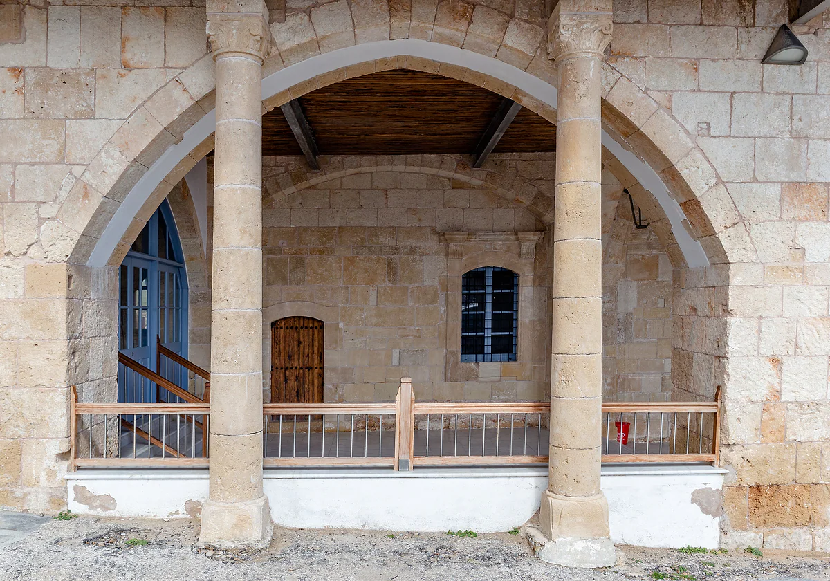 The pointed-arch porch of a building at Apostolos Andreas Monastery, in pale stone, with wooden doors and a balcony