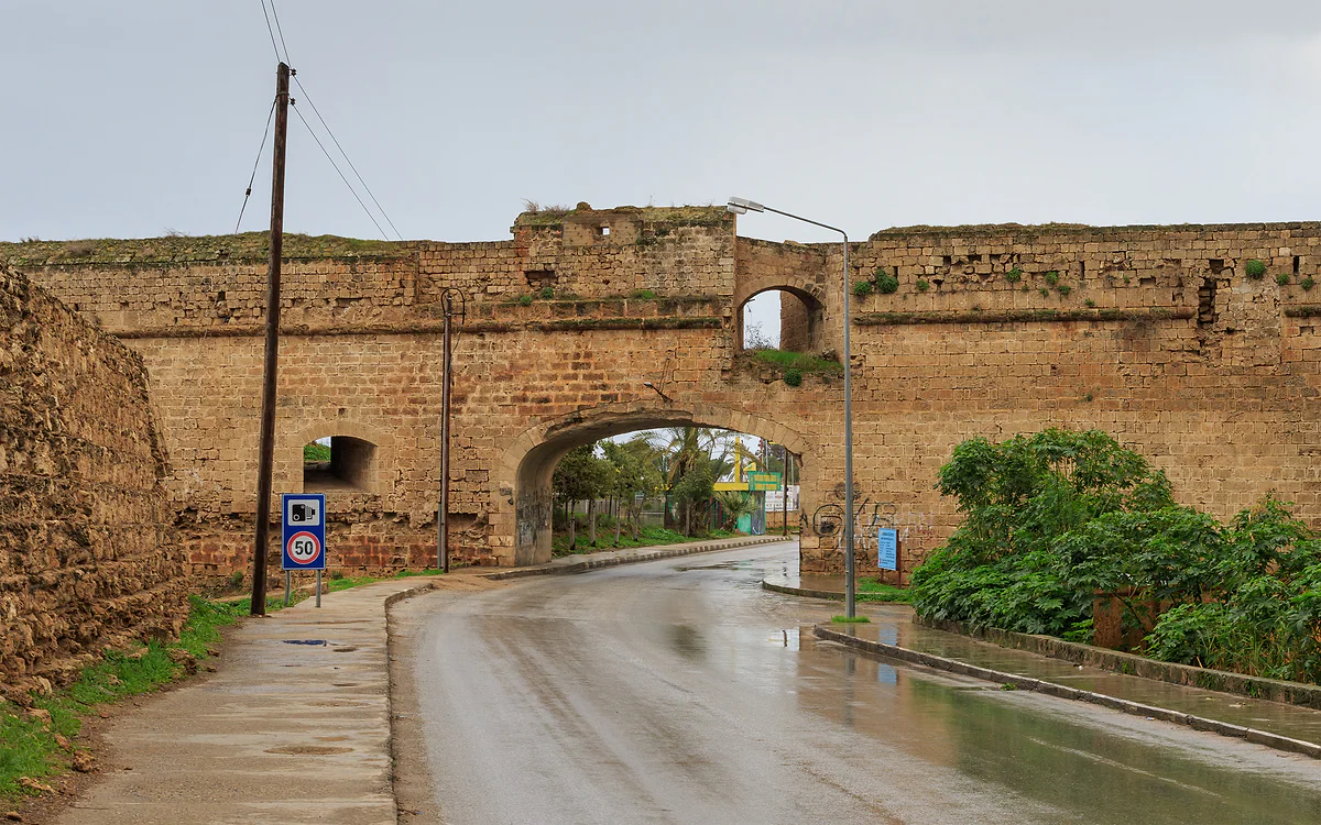 A stretch of Famagusta's stone city walls with an arch carrying a rain-soaked road through it
