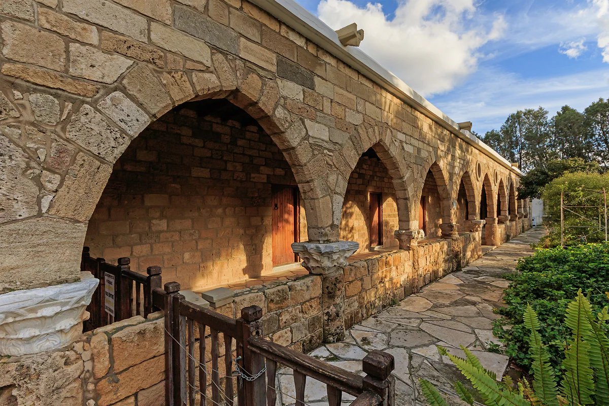 The stone arcades of the monastery of Saint Nicholas of the Cats at Akrotiri, with plants beside the path