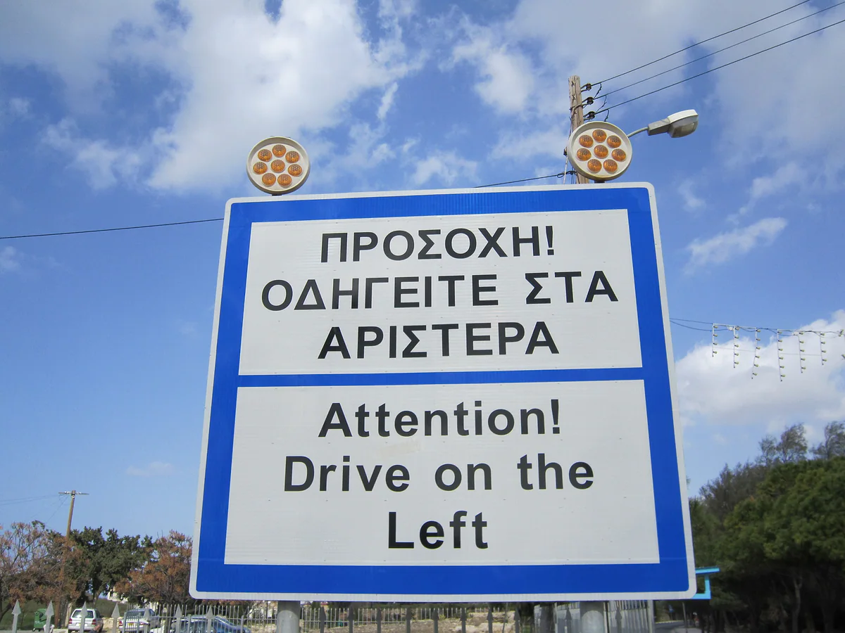 A bilingual Greek and English road sign warning drivers that traffic in Cyprus keeps to the left