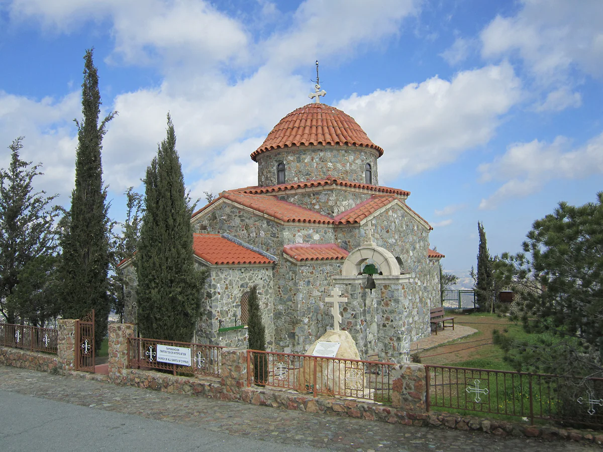 The All Saints chapel beside Stavrovouni Monastery, built of stone with a red-tiled dome among cypress trees