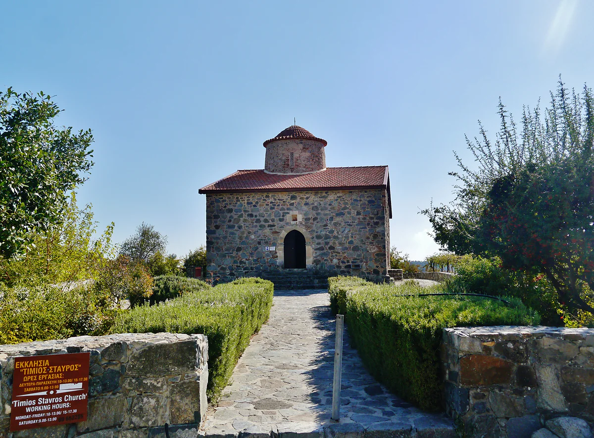 The church of Timios Stavros at Pelendri, a stone building with a dome at the end of a path between hedges and gardens