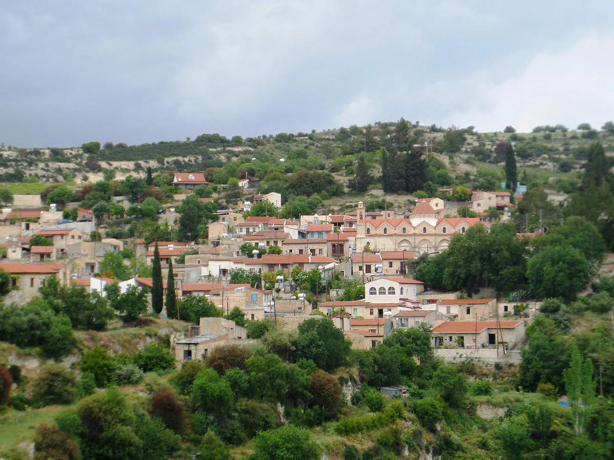 Another view of Vasa Koilaniou with houses stepped along the hillside, tall cypresses and green vegetation in spring