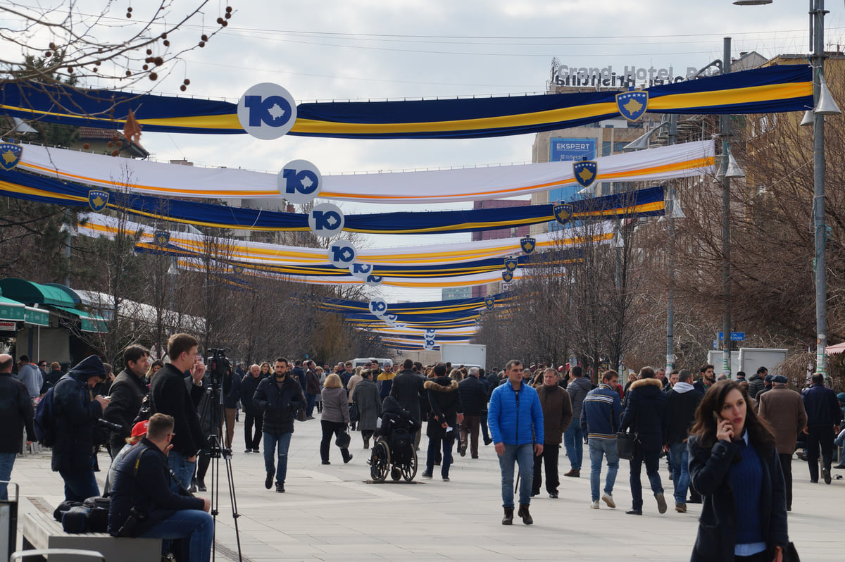 Pristina's pedestrianised Mother Teresa Boulevard busy with walkers, with strings of coloured bunting hung above the street