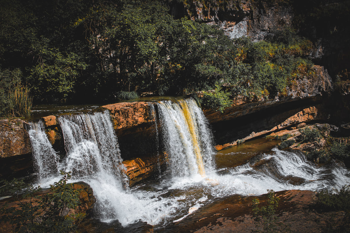 One of the Mirusha waterfalls tumbling over rock ledges among trees, with the water blurred in motion