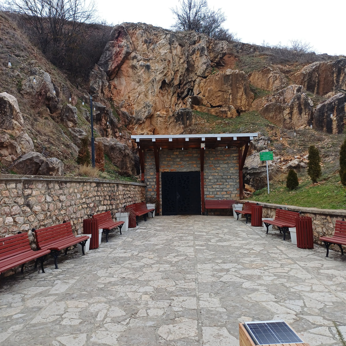 The entrance to the Marble Cave at Gadime, with red benches in front and the rock face rising above it