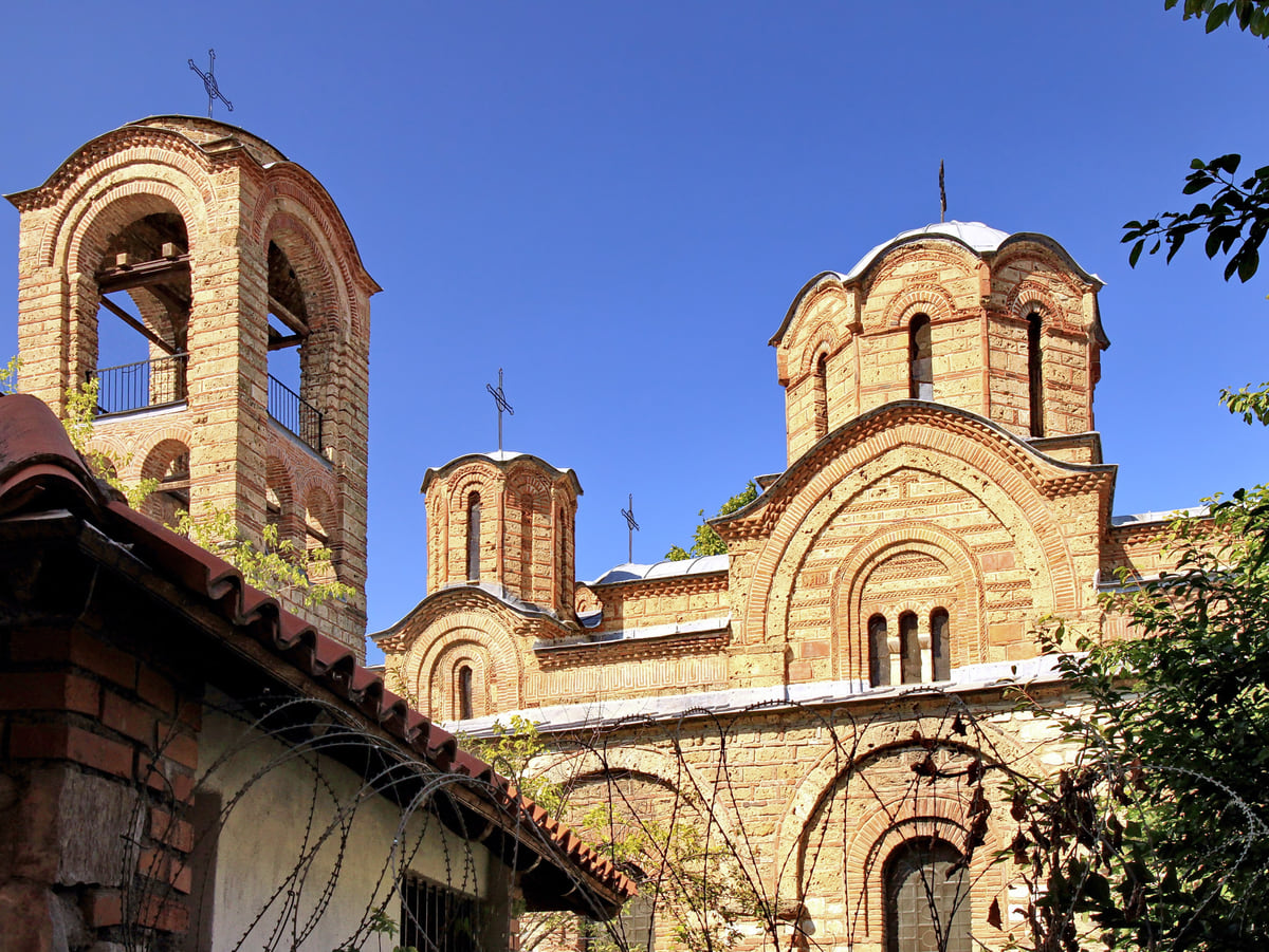 The Church of the Virgin of Ljeviš in Prizren, in brick and stone, with its bell tower and domes under a blue sky