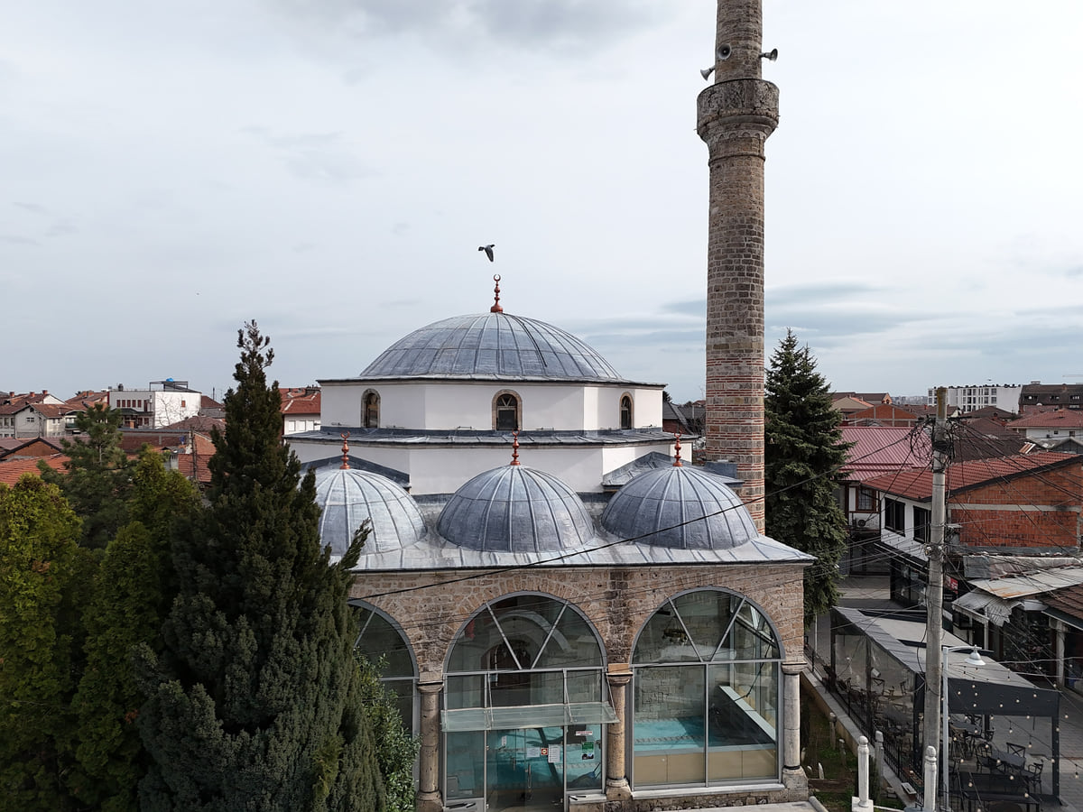 The Bajrakli Mosque in Peja with its grey lead domes and white minaret, rising among the rooftops of the centre