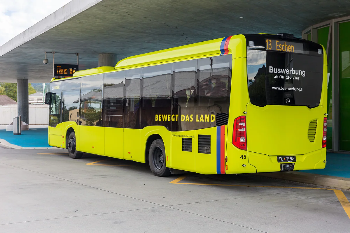 Un autobús LIEmobil de color lima en la estación de autobuses de Schaan, con el letrero de la línea 13 a Eschen.