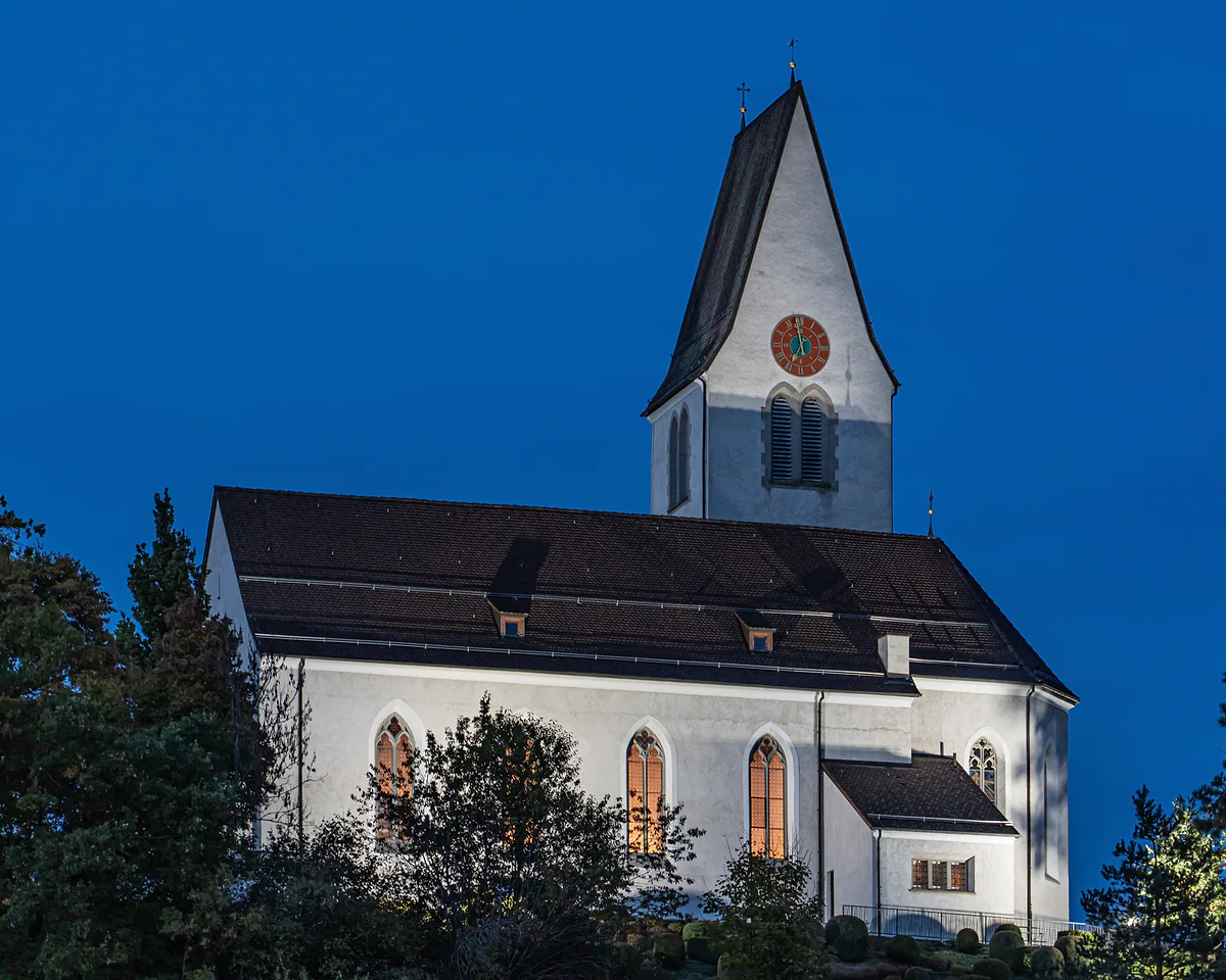 La iglesia parroquial de Bendern en la hora azul, con las ventanas iluminadas y el campanario de reloj.