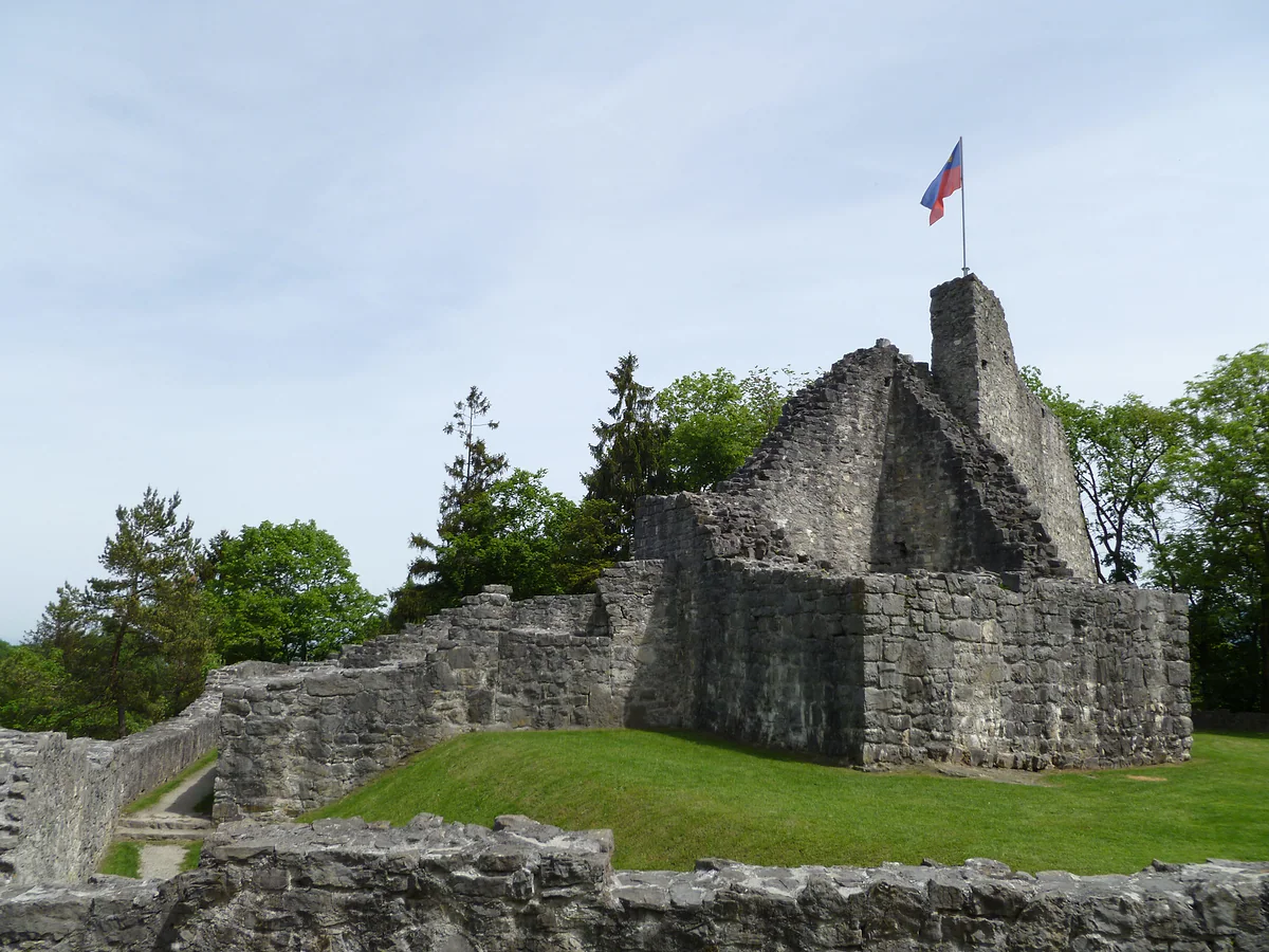 Las ruinas de piedra del castillo alto de Schellenberg, con la bandera de Liechtenstein en lo alto de la torre.