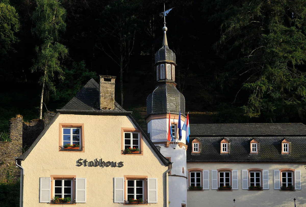 The Stadhous, Vianden's town hall, with a white façade, shutters, window boxes and a small tower with flags