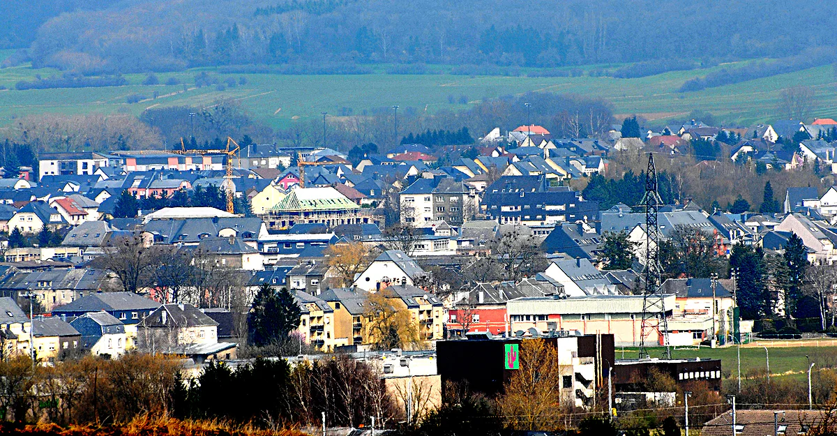 Bascharage, in the commune of Käerjeng, with its houses and rooftops spread across the plain and green hills behind