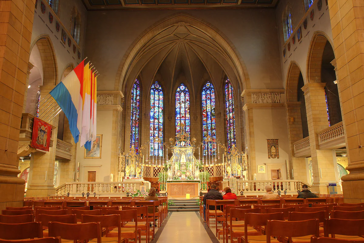 The choir of Notre-Dame Cathedral with its altar, stained-glass windows and Luxembourg flags hanging in the nave