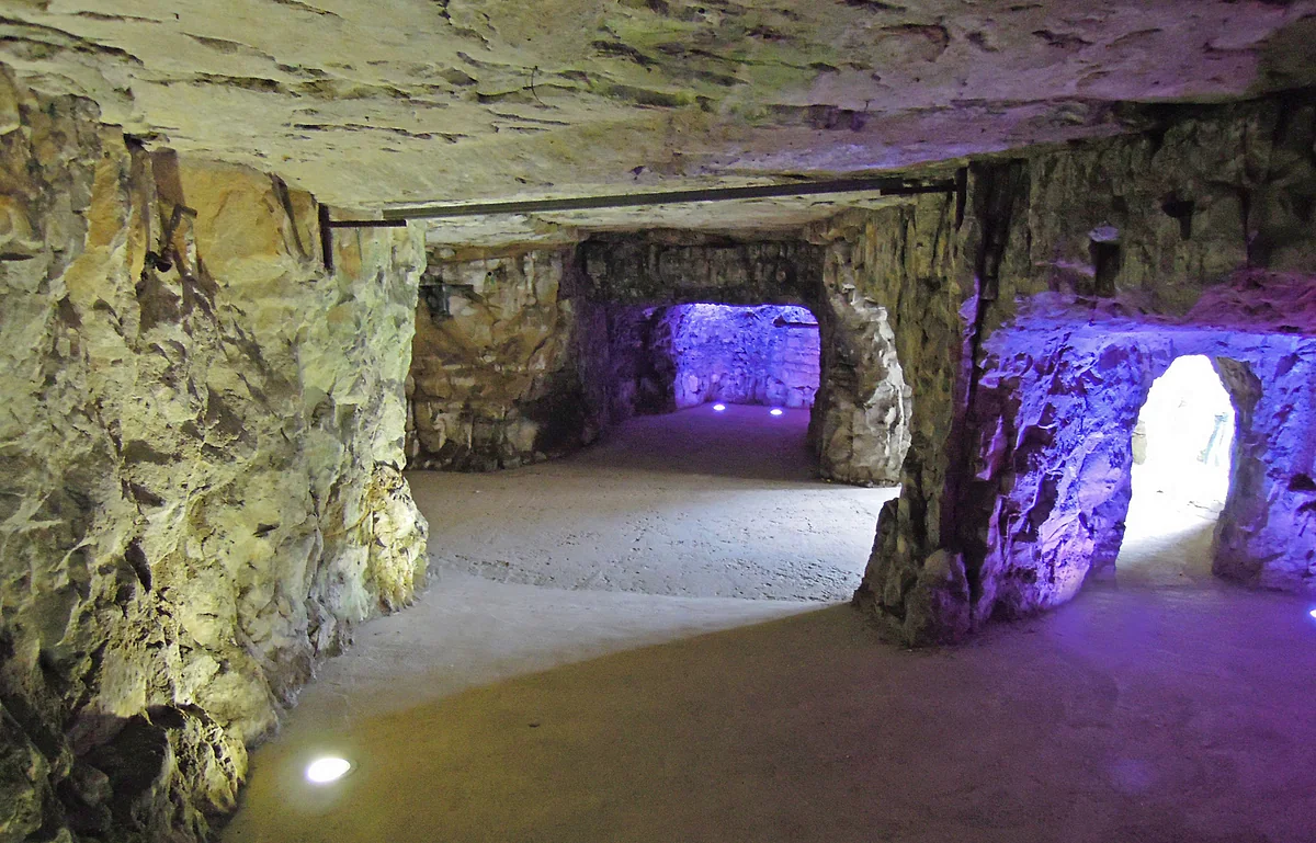 A gallery cut into the rock of the Bock Casemates, with passages lit in shades of purple and gold