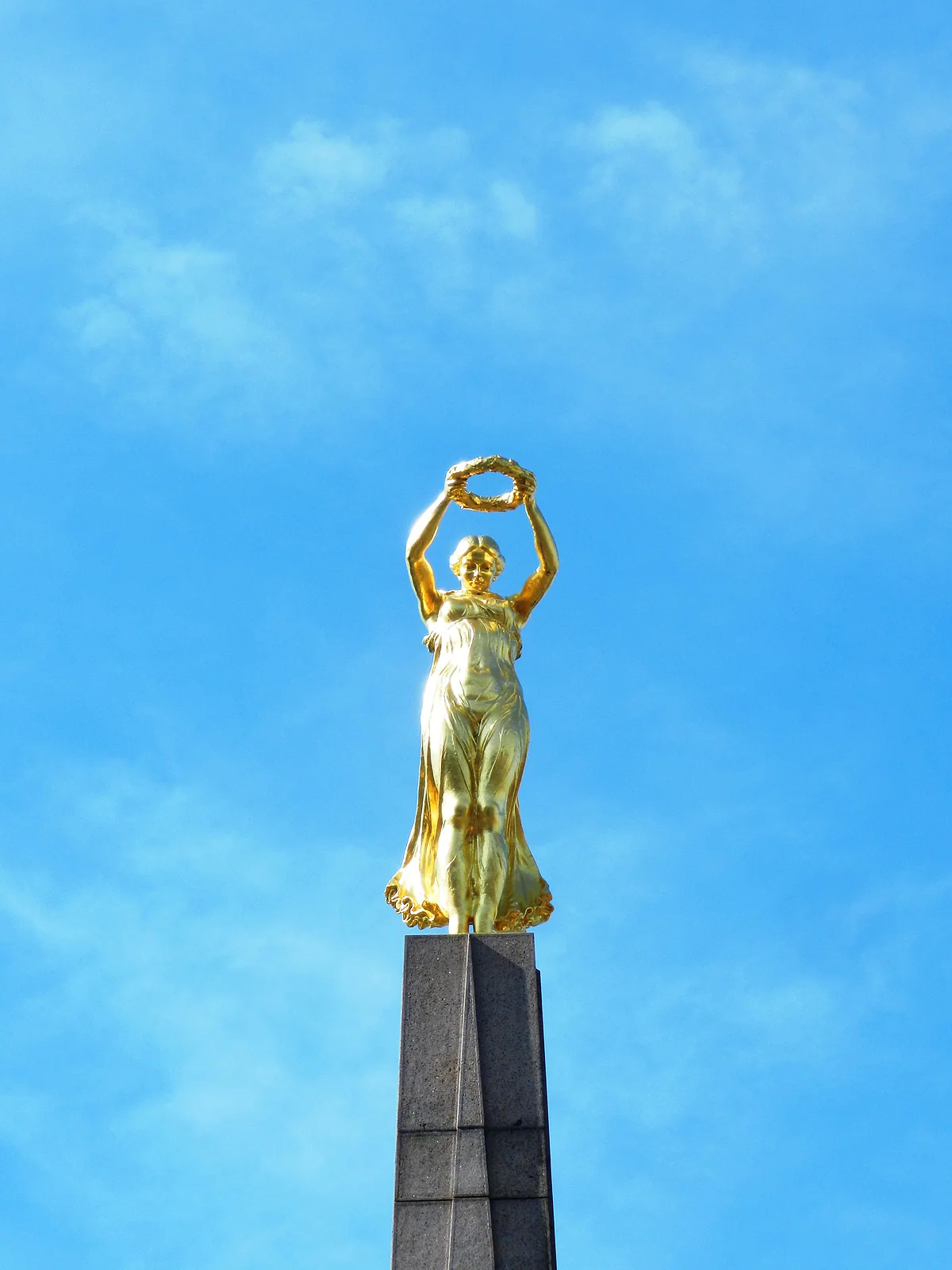 The Gëlle Fra, a golden figure holding up a laurel wreath, atop the obelisk of the Monument of Remembrance