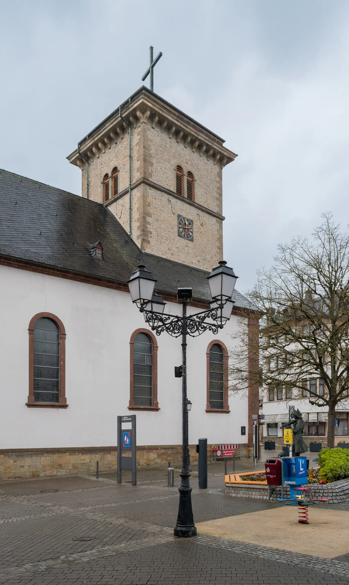St Lawrence's Church in Grevenmacher, white with a stone tower, and an iron lamp post on the square in front