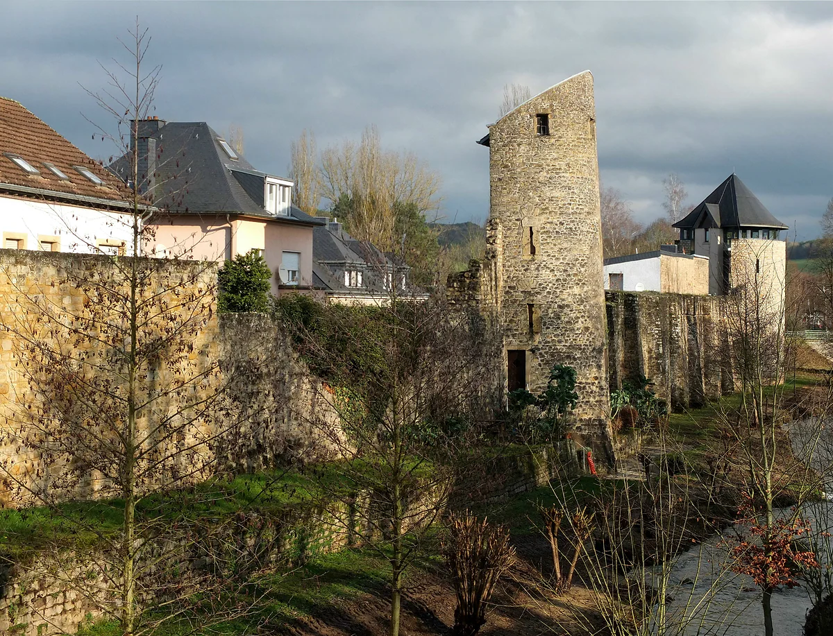 The southern stretch of Echternach's medieval town wall, with a stone tower and whitewashed houses behind