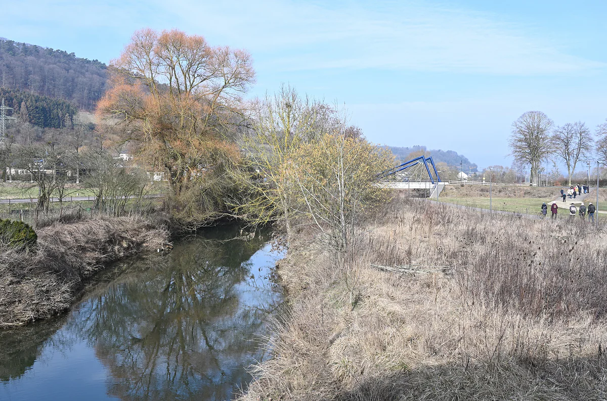 The River Alzette at Lintgen seen from the footbridge, with dry grassy banks, willows and hills beyond