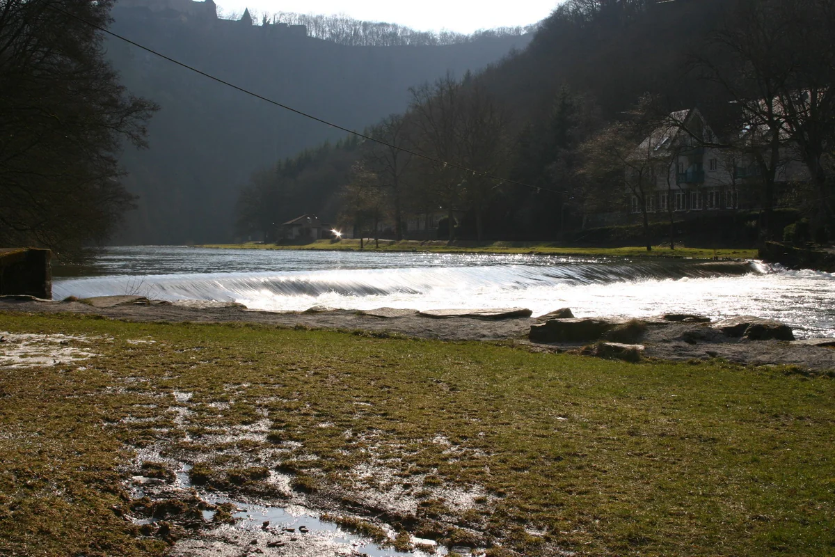 The River Sûre forming a small weir by Bourscheid-Plage, in a deep valley with forest-covered slopes