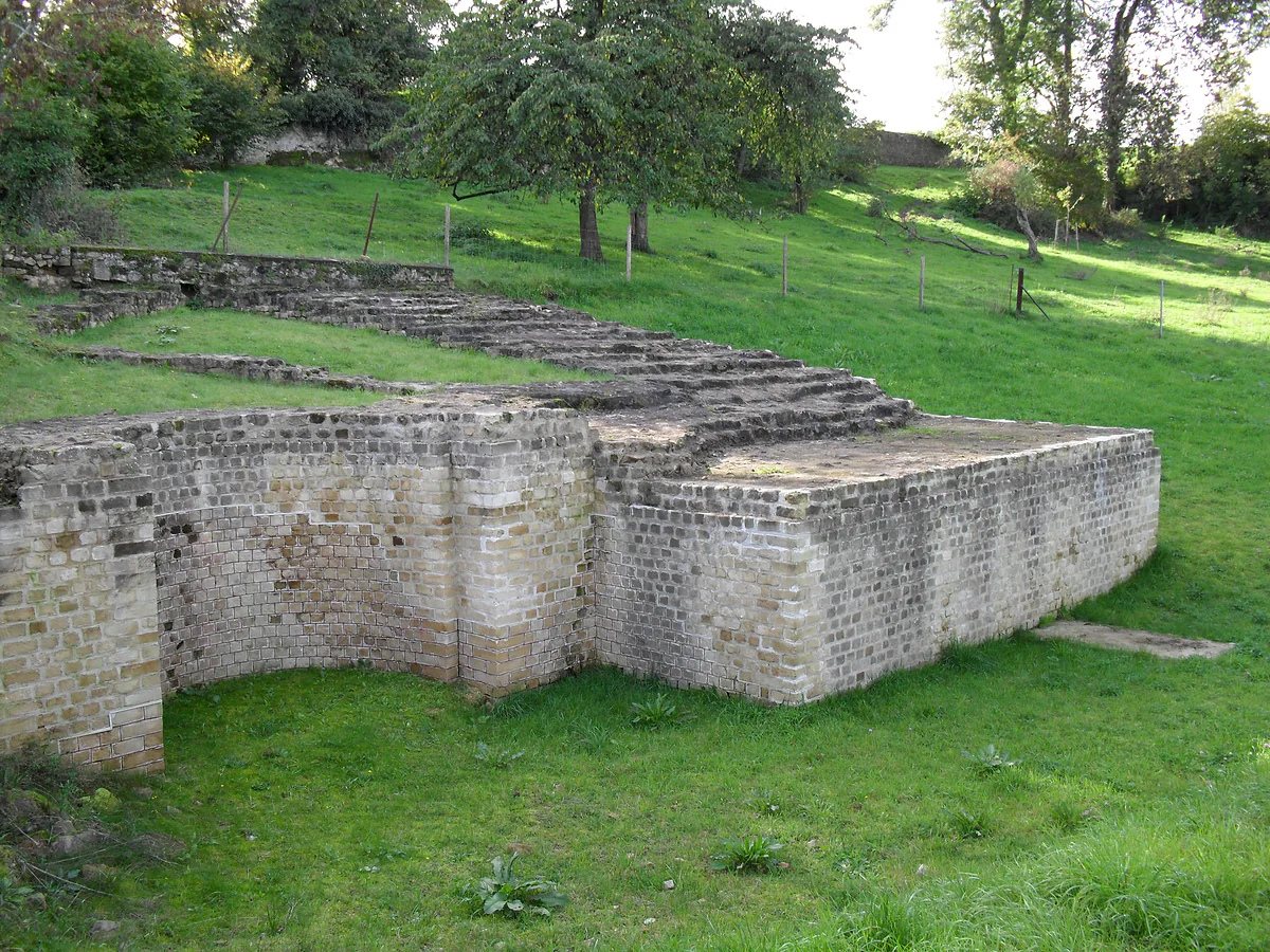 The remains of the Roman theatre at Dalheim, with stone tiers and walls set into a grassy, tree-lined slope
