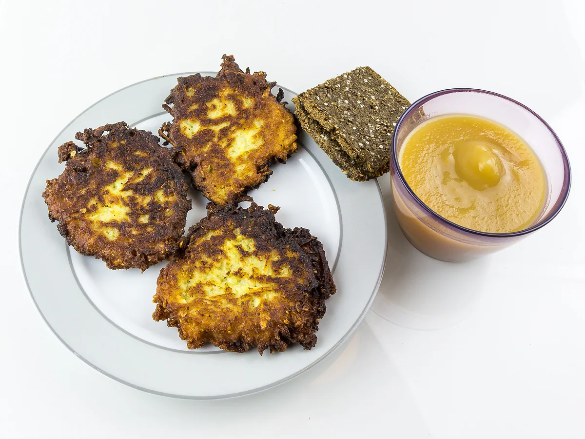 Fried grated potato pancakes, like Luxembourg's Gromperekichelcher, with apple sauce and dark rye bread