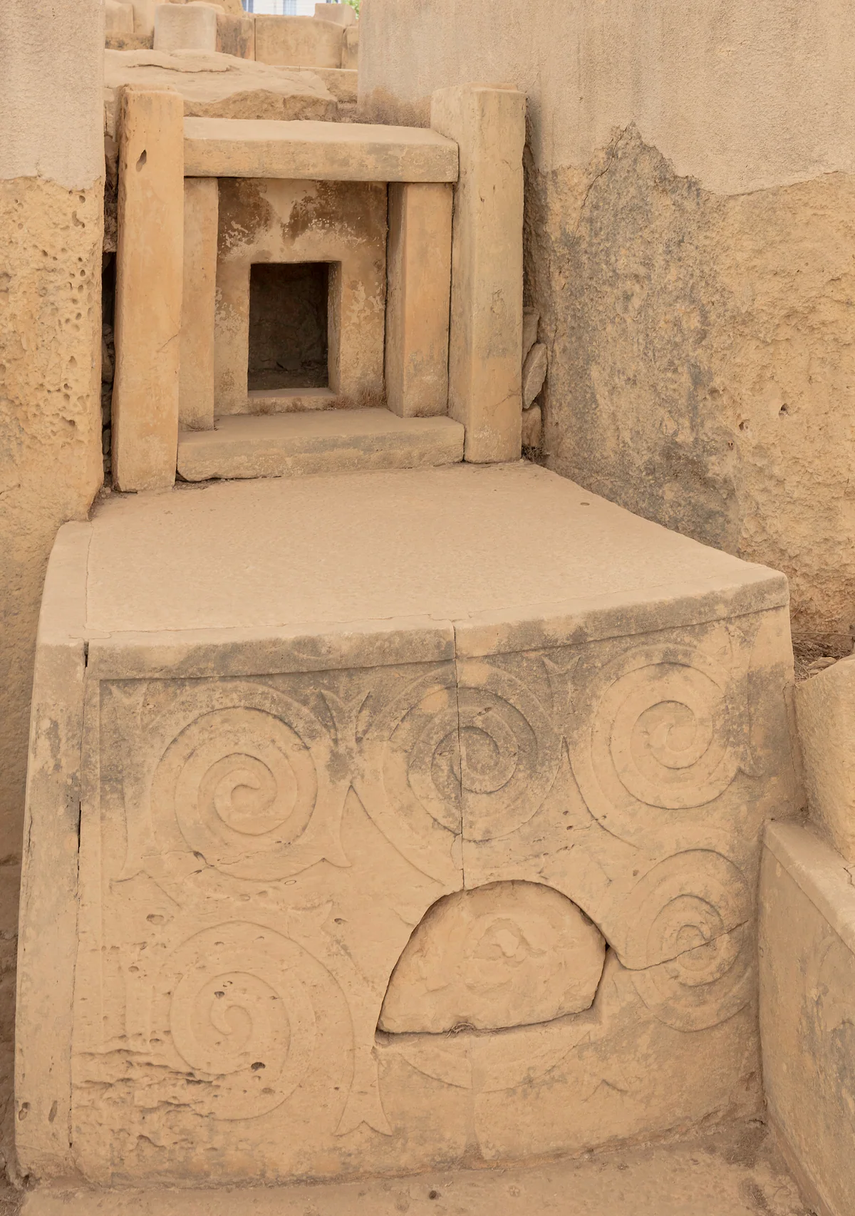 Un altar de los templos de Tarxien decorado con espirales talladas en la piedra, ante un nicho con dintel al fondo del santuario.