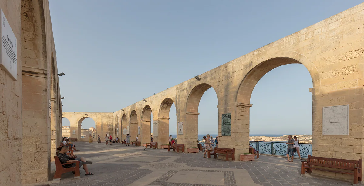 Las arcadas de piedra de los jardines Upper Barrakka de La Valeta, con bancos a la sombra y el mirador abierto sobre el Gran Puerto.