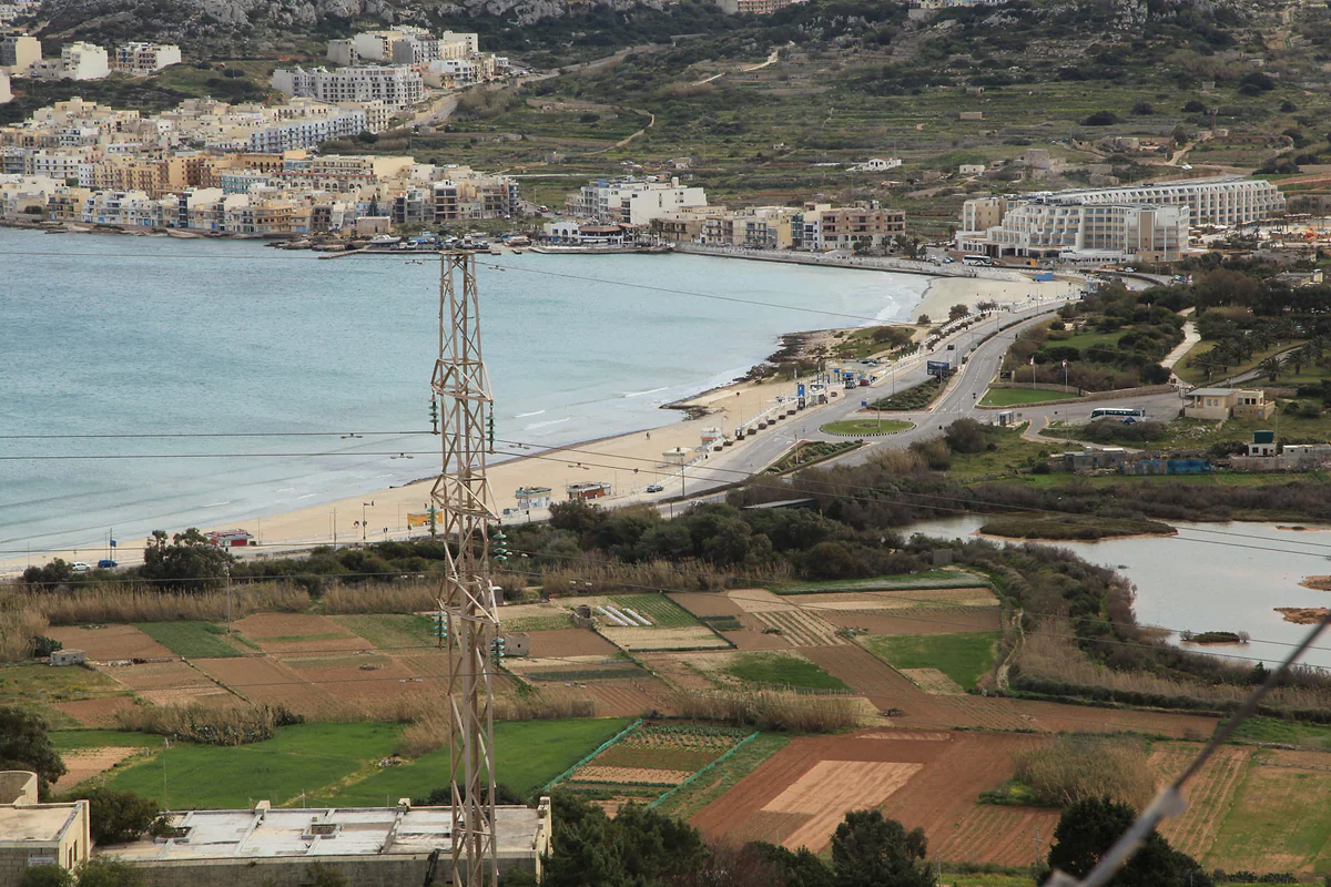 La bahía de Mellieħa con la larga playa de arena de Għadira, la reserva natural de las salinas detrás y el pueblo en la ladera.