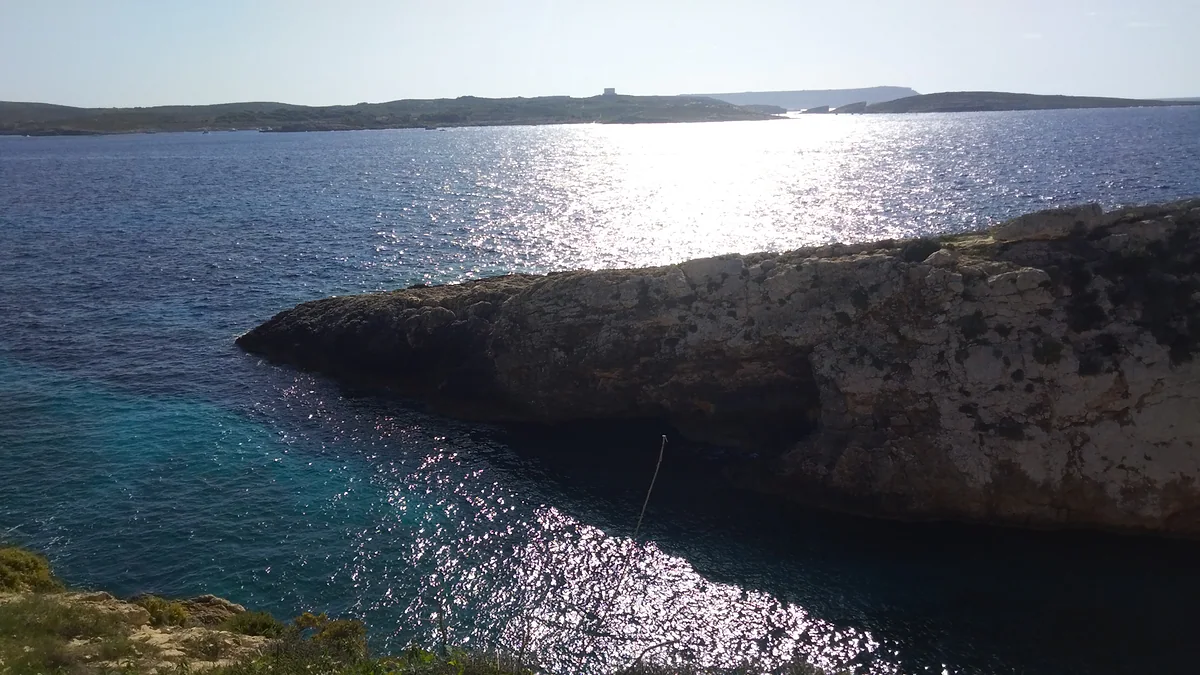 La cala de Ħondoq ir-Rummien, en Qala, con el agua transparente entre las rocas y Comino al otro lado del estrecho.