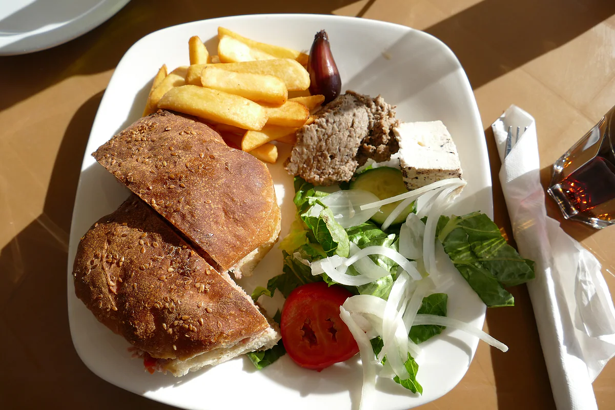 Una ftira maltesa rellena de atún, tomate y alcaparras, servida con patatas fritas y ensalada en un bar de Marsaxlokk.